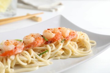 Delicious pasta with shrimps and green onions on white table, closeup