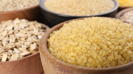 Different types of cereals in bowls on table, closeup