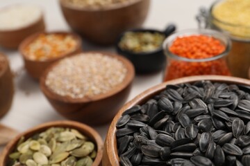 Different types of seeds, cereals and legumes on white table, closeup