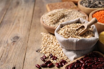 Different types of cereals and legumes on wooden table, closeup. Space for text