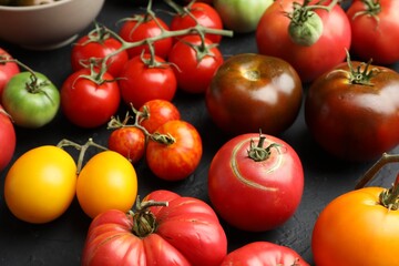 Many different fresh tomatoes on grey table, closeup