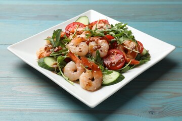 Delicious shrimp salad with vegetables on light blue wooden table