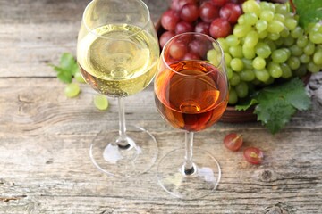 Fresh ripe grapes and glasses of wine on wooden table, closeup