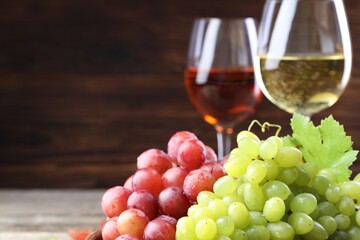 Fresh ripe grapes and glasses of wine on wooden table, closeup. Space for text
