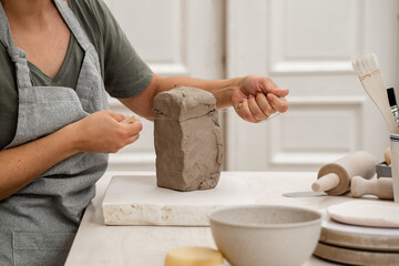 Wire clay cutter to cut clay from a large block. Cutting off the necessary piece of clay before forming a pottery product. Learning how to cut clay on ceramics workshop.