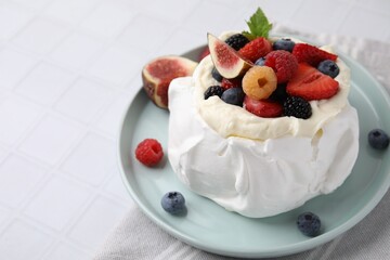 Pavlova cake (meringue dessert) with whipped cream, fresh berries, mint and fig on white tiled table, closeup