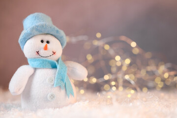 Funny snowman figure on artificial snow against blurred lights