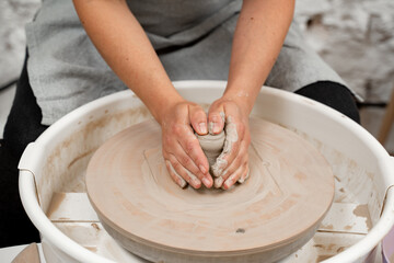 Girl is making a bowl on a pottery wheel with your own hands. Forming the proper size and shape of pottery with increasing speed of a pottery wheel.