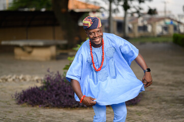 Handsome young Yoruba man performing traditional Komole dance at cultural event in vibrant attire