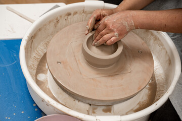 Creating a ceramic bowl by yourself in a pottery class. Wheel throwing. Learning how to model clay into different shapes with pottery wheel.