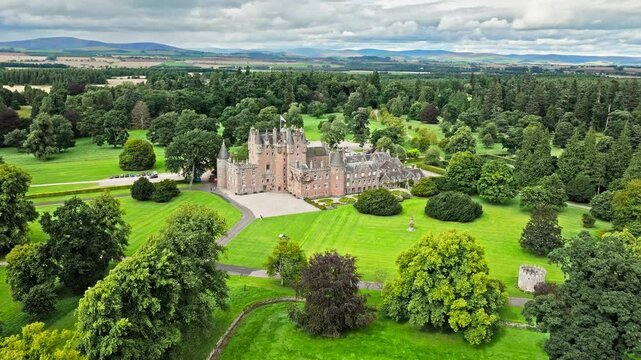 Drone view of Glamis Castle with towers and beautiful garden in Scotland. Aerial view of Scottish landmark with thick walls, and a modern parapet.