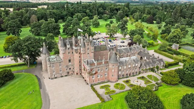Drone view of Glamis Castle with towers and beautiful garden in Scotland. Aerial view of Scottish landmark with thick walls, and a modern parapet.