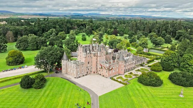 Drone view of Glamis Castle with towers and beautiful garden in Scotland. Aerial view of Scottish landmark with thick walls, and a modern parapet.