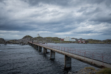 Obraz premium Footwalk concrete bridge over rough sea towards light house in Norway