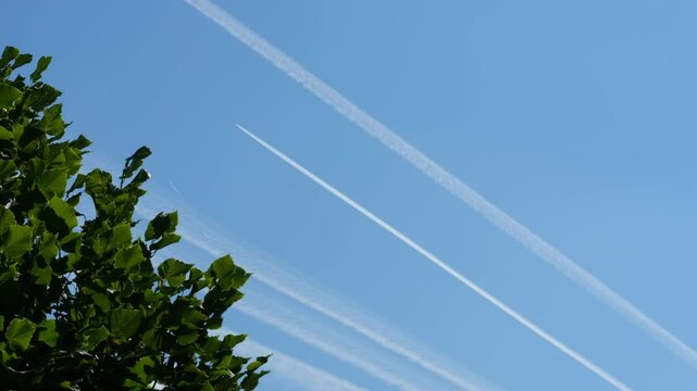 Blue sky with a flying plane and condensation trails (contrails) on it