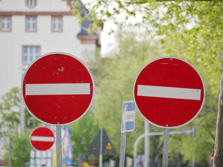 three no entry one way traffic signs standing close to each other on a street in a city