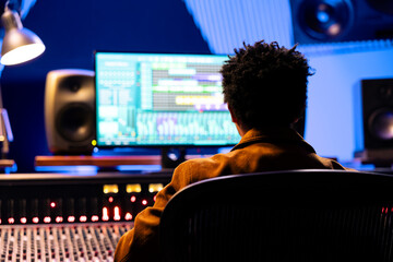 African american record composer mixing and mastering songs with audio software, working with auto...