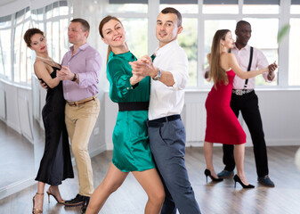 Graceful woman and young man practicing waltz in pair in dancing studio
