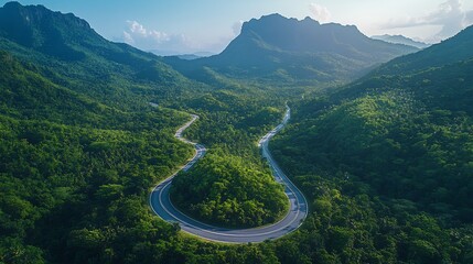 Beautiful mountain road winding through lush forests a clear blue sky above