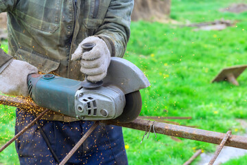 Worker cut metal frames with hand saw using angle grinder