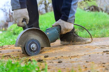 An angle grinder hand saw is used by worker when cutting metal