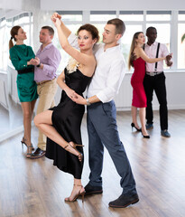 Graceful woman and young man practicing waltz in pair in dancing studio