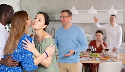 Happy middle-aged pair welcoming their guests during small gathering with close friends at home
