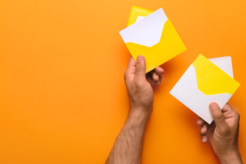 Male hands with envelopes and blank cards on color background, closeup