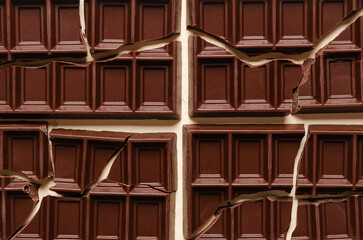 Background of broken dark chocolate bars in rectangular format. Top view. 