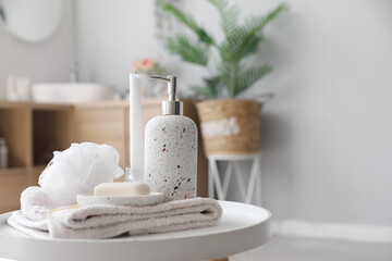 Soap bar, dispenser, shower sponge, towel and candle on table in bathroom, closeup