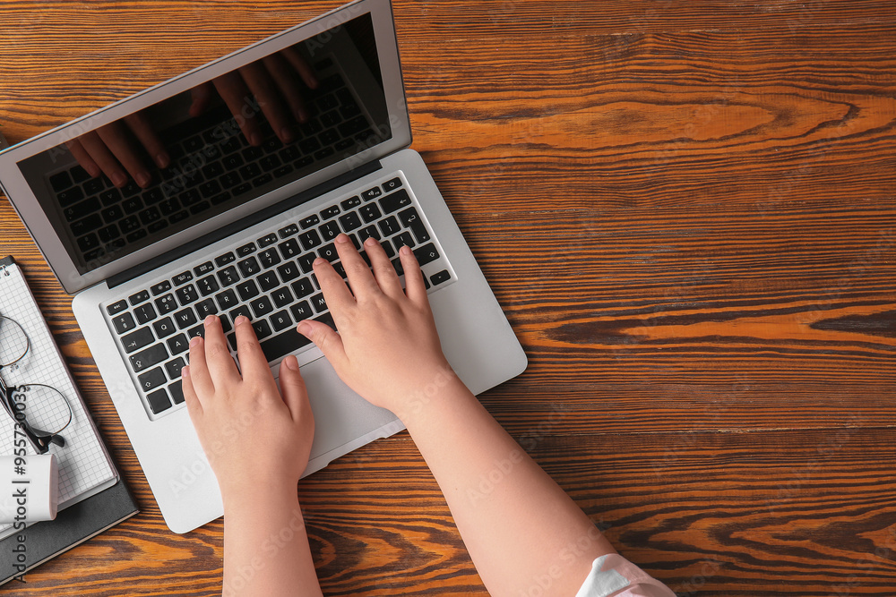 Poster Female programmer using laptop with eyeglasses on wooden background