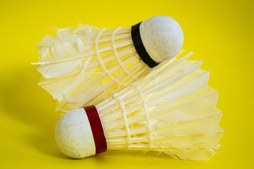 a used badminton ball or shuttlecock with a yellow background, white in color and made of goose feathers and used in badminton games.