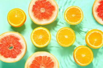 Slices of fresh orange and grapefruit in water on turquoise background