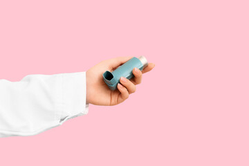 Female doctor hand with inhaler on pink background