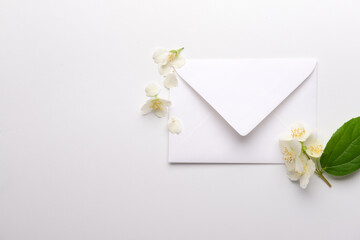 Composition with envelope and beautiful jasmine flowers on light background