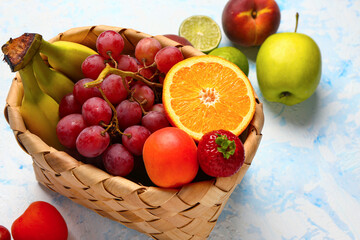 Wicker basket with different fresh fruits on light blue background