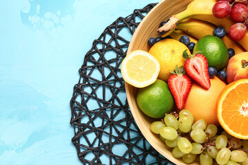Bowl with different fresh fruits on blue background