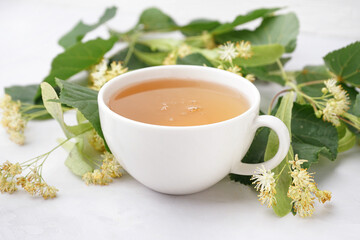 Cup of linden tea and leaves on white background