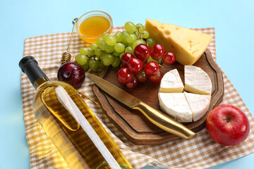Composition with tasty food for picnic, bottle of wine and honey on blue background, closeup