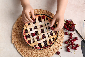 Woman decorating tasty cherry pie on white background