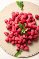 Heap of fresh raspberries and mint on white background