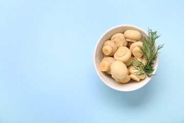 Bowl with canned mushrooms on blue background