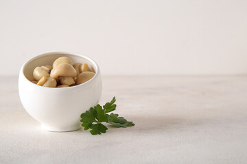 Bowl with canned mushrooms on light background