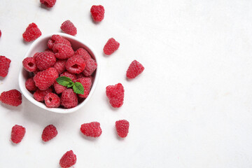 Bowl with fresh raspberry and mint on light background