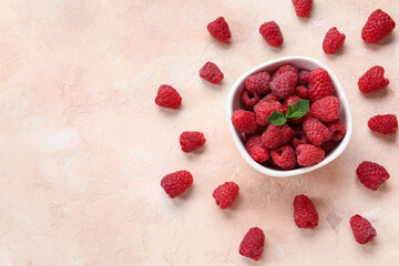 Bowl with fresh raspberry and mint on beige background