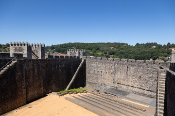 Sabugal Castle in Portugal features imposing stone walls and a historic stone staircase, showcasing its medieval architecture. The image captures the fortress under a clear blue sky