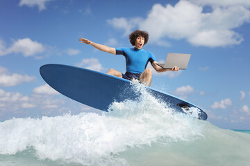 Man in a wetsuit surfing with a laptop