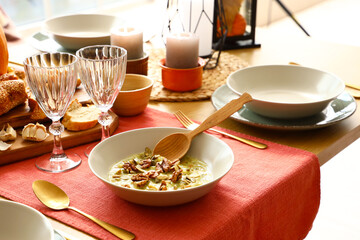 Creamy soup with walnuts and pumpkin seeds in bowl on table, closeup