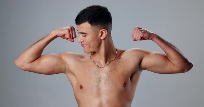 Face, flexing and man with fitness, biceps and wellness with bodybuilder on gray studio background. Portrait, person and model showing muscle, training and workout with confidence, pride and athlete