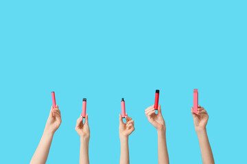 Many hands holding electronic cigarettes on blue background